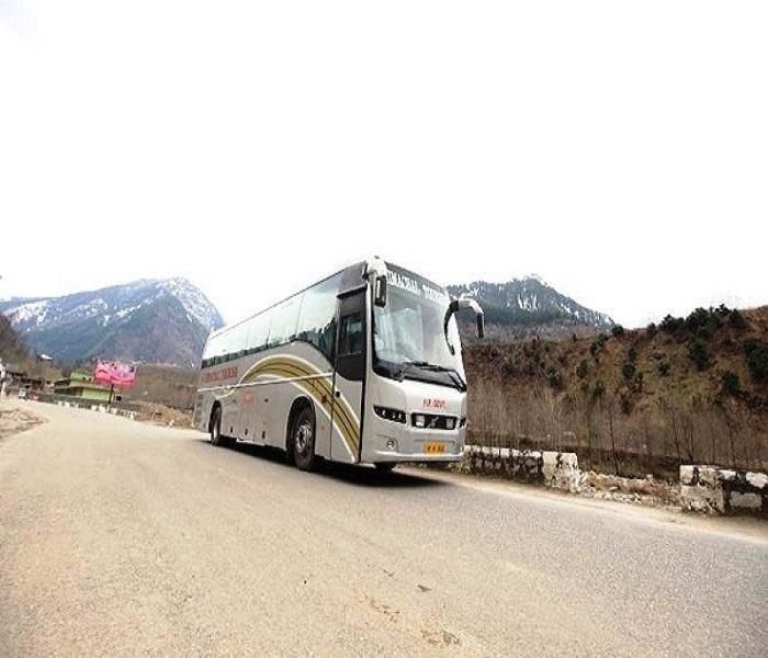Volvo bus traveling from Delhi to Manali through scenic mountain roads in Himachal Pradesh